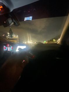 the interior of a car at night with city lights in the background