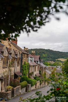 an old street with stone buildings on both sides and trees in the foreground, surrounded by greenery