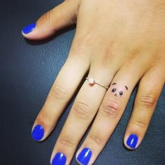 a woman's hand with blue nail polish and a smiley face on her ring