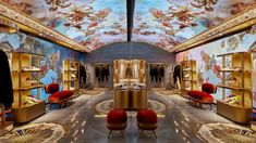 the inside of a store with gold furniture and paintings on the ceiling, along with red chairs