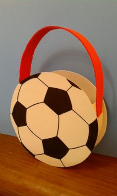 a paper bag with a soccer ball on it sitting on a wooden shelf next to a wall