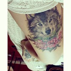 a woman's thigh with a wolf tattoo on it and roses around her ankles