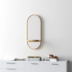 an oval mirror on the wall above a white dresser