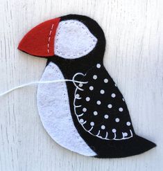 a black and white bird with a red beak sitting on top of a wooden table