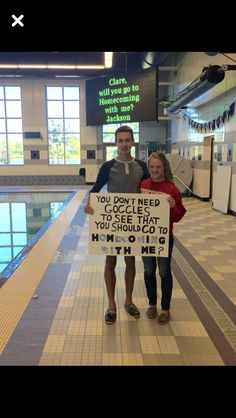 two people standing next to each other holding a sign that says you don't need to see that you should go swimming