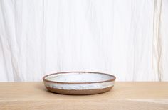 a white and brown bowl sitting on top of a wooden table