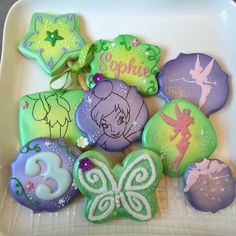 decorated cookies in the shape of fairy princesses on a white plate with purple and green icing