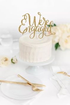 there is a cake with the word we're engaged on it and two forks next to it