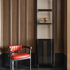 a red chair sitting in front of a tall book shelf next to a wooden wall