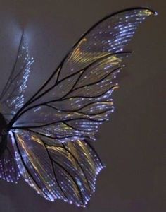 a close up of a butterfly flying in the air with lights on it's wings