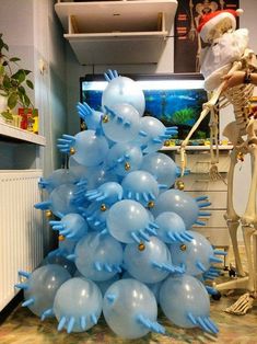 a christmas tree made out of balloons in the shape of fish and skeleton with santa claus's hat on