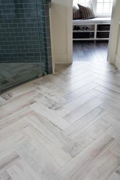 a bathroom with wood flooring next to a glass shower door and bench in the corner