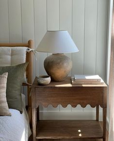 a table with a lamp on it next to a bed