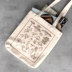 "This stylish tote bag features beautiful botanical illustrations printed on a premium canvas bag measuring at 16\" H x 15\" W. These beautiful everyday use tote bags have 100% cotton sheeting with reinforced handle stitching to ensure a reliable bag rich in both practicality and durability. ✅ Material: 100% cotton sheeting 💗 Lightweight and compact ❇️ Handle Length: 20\"  Our designs are fulfilled by Printify. This ensures a quality product custom engineered with advanced printing technology s Messenger Bag School, Mushroom Tote Bag, Mushroom Bag, Canvas Tote Bag Aesthetic, Tshirt Inspiration, Aesthetic Mushroom, Aesthetic Cottage Core, Aesthetic Cottage, Boho Tote Bag