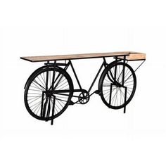 an old fashioned bicycle is mounted to the wall with a wooden table on it's side