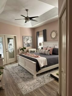 a bed room with a neatly made bed and a ceiling fan in it's corner