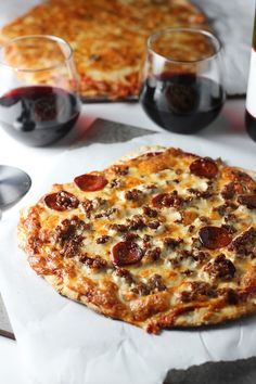 two pizzas sitting on top of a table next to a bottle of wine