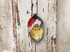 a painted rock hanging on the side of a wooden door with a red hat and flower