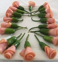 a white plate topped with green beans and ham wrapped in rolled up flowers on top of each other