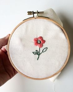 a hand holding a small embroidered red flower