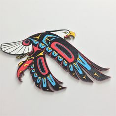 a colorful bird shaped brooch sitting on top of a white surface