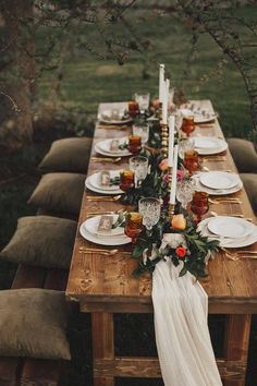 a long wooden table topped with plates and candles