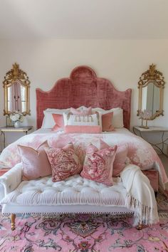 a bed with pink and white pillows on top of it in a room filled with mirrors