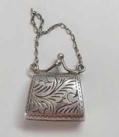 Sterling silver vintage purse charm locket. It has a hinge on the bottom so it can open up. The clasps at the top snap it tight. 4.9 grams  **This is one of our beautiful and unique vintage pieces that we purchased "over the counter" or from an estate sale.  Each piece goes through our Accredited Gemologist Association AGA certified laboratory to check the identity of the stones, metal type and quality.  It is preloved and in great condition.  We enjoy these pieces of history that give us a glimpse of the past but we are not a museum.  We price our jewelry to sell to keep our inventory moving forward and fresh.  Check back often to see new listings.  Thank you for visiting our shop.  Please contact us with any questions. Vintage Rectangular Jewelry For Everyday Use, Elegant Silver Locket Necklace Stamped 925, Silver Sterling Silver Locket Necklace For Formal Occasions, Antique Sterling Silver Locket Necklace For Formal Occasions, Collectible Hallmarked Silver Locket Necklace, Silver Hallmarked Locket Necklace Collectible, Vintage 925 Stamped Jewelry Keepsake, Vintage Stamped 925 Jewelry Keepsake, Rectangular Silver Necklaces For Everyday Use