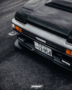 the front end of a black car parked in a parking lot