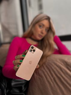 a woman sitting on a couch holding an iphone in her hand and looking at the camera