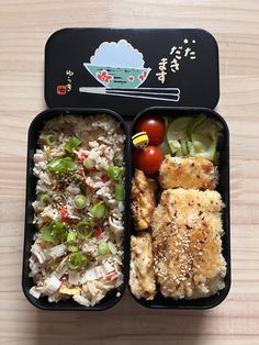 two black trays filled with rice, meat and veggies on top of a wooden table