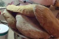 there is a large loaf of bread sitting on top of someones lap in the kitchen