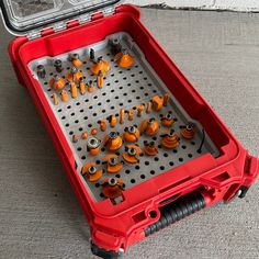 a red case filled with lots of orange and black screwdriver sets on top of a gray floor