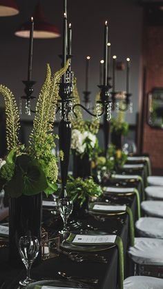 a long table is set with black and white tables cloths, green centerpieces, and silverware