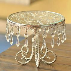 a glass table with some crystal beads on it and a metal stand that is sitting on a wooden surface