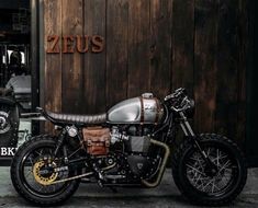 a motorcycle parked in front of a wooden building with the name zeius on it