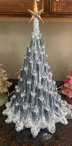 a christmas tree made out of plastic bottles on a counter with other ornaments in the background