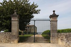 an iron gate with two pillars leading to a house