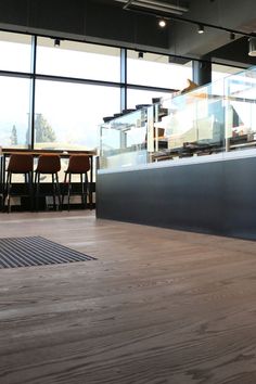 a man riding a skateboard on top of a wooden floor next to tall windows