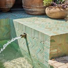 a water fountain is shown with potted plants in the background