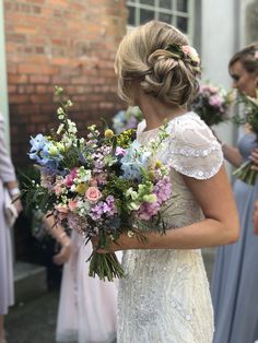 a woman holding a bouquet of flowers in her hand and looking at the other bridesmaids