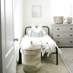 a bedroom with a bed, dresser and baskets on the floor in front of it