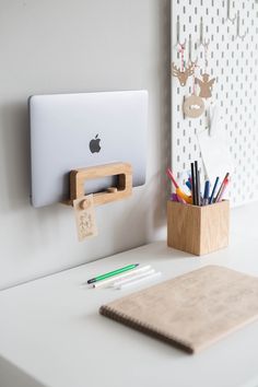 an apple computer sitting on top of a desk next to a pen holder and pencils