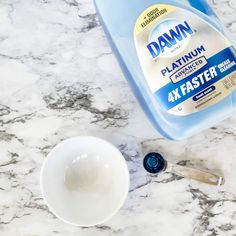 a bottle of dawn dish soap next to a measuring cup on a marble countertop