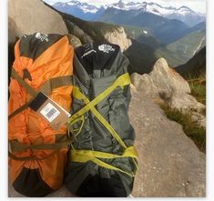 two bags sitting on top of a mountain next to each other with mountains in the background