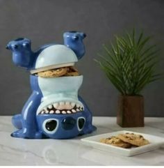 a cookie jar with cookies in the shape of a monster and teeth on it, sitting next to a plate of cookies