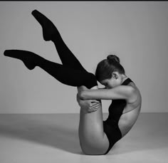 a woman in black leotard and tights posing for the camera with her legs crossed