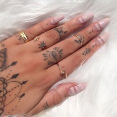 a woman's hand with tattoos on it and two rings in the middle of her fingers