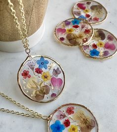 Oh wildflowers 🌸 is there anything better? This big circular pendant is made of real pressed flowers preserved into resin. There is gold leafing sprinkled into the resin to make the pendant really sparkle ✨This is made to last a long time and the high quality resin preserves the flowers to stay at this vibrancy for as long as the necklace lasts! The pendant is on a super long 28 inch chain with NO clasp. You can easily slip this over your head without having to mess with the closure in the back Botanical Style Gold Resin Jewelry, Bohemian Gold Resin Necklace, Resin Necklace With Pressed Flowers In Round Pendant, Round Resin Pendant Necklace With Pressed Flowers, Gold Resin Flower Pendant Jewelry, Gold Resin Necklace With Birth Flower, Gold Resin Necklace With Birth Flower Detail, Gold Resin Round Pendant Necklace, Gold Birth Flower Necklace In Resin