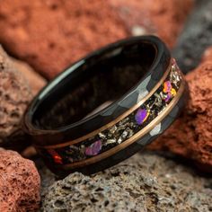 a black ring with colorful flowers on it sitting on some rocks next to red rocks